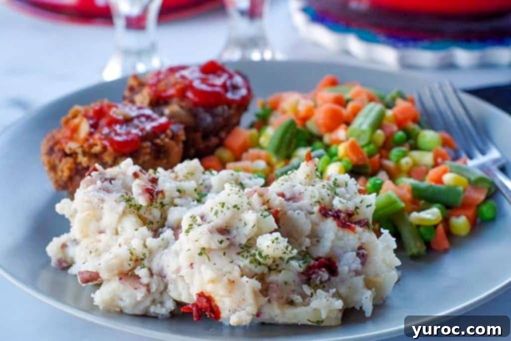 Chipotle mashed potatoes on a plate with mixed vegetables and mini meat loaves.