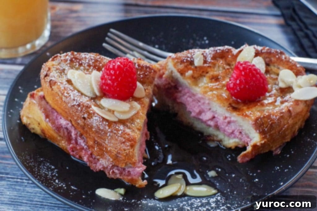 Raspberry Cream-Filled French Toast Sandwich 3 Raspberry French Toast Sandwich cut in half on a black plate, with fork on plate