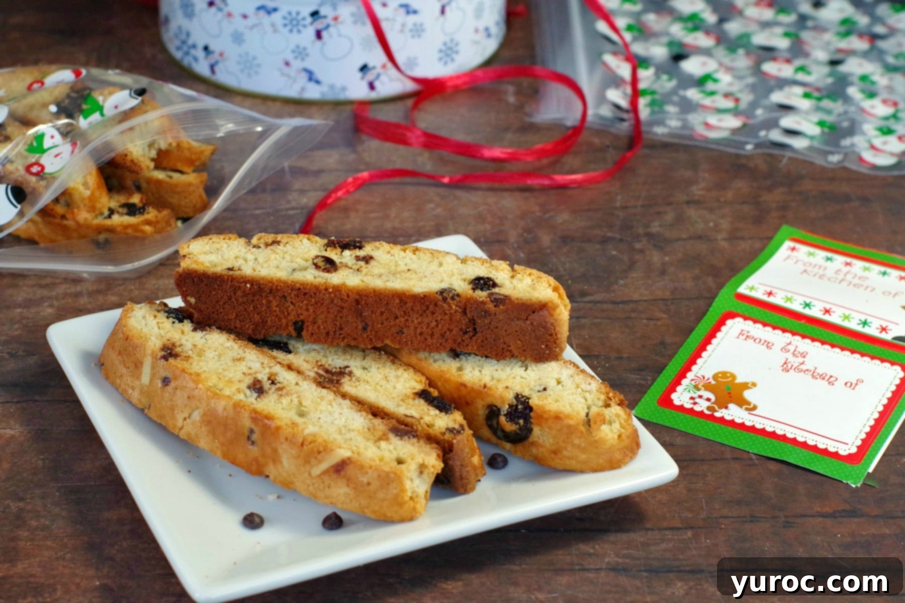 Several Black Forest biscotti cookies artfully arranged on a white plate, with a vintage-style tin filled with more biscotti visible in the background.