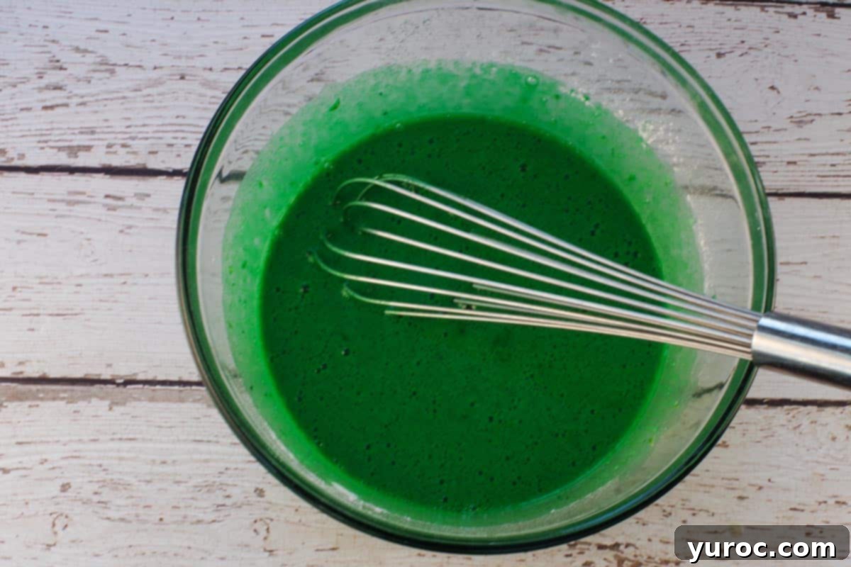 Flour mixture, food coloring and lime zest whisked into the large glass bowl with egg mixture.