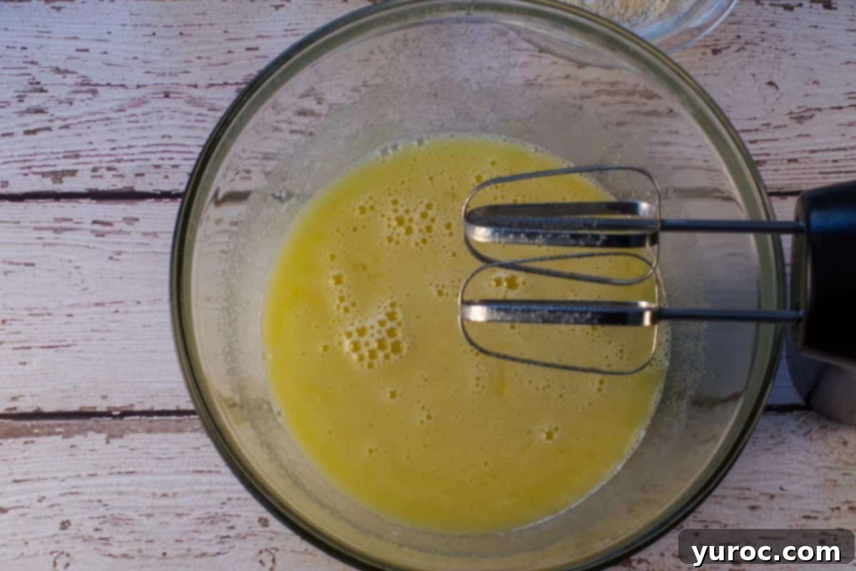 Eggs, lime juice and white sugar beaten together with an electric mixer, in a large glass bowl, with beaters over bowl.