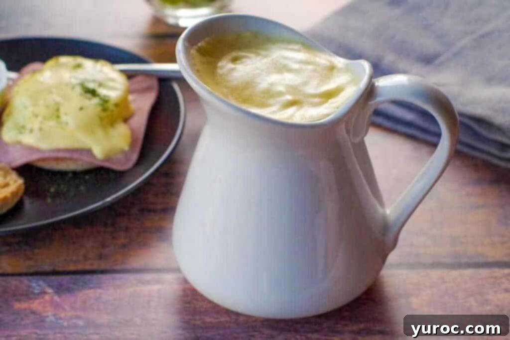 Lighter Hollandaise 2 Healthy Hollandaise sauce in a large white creamer with plate of eggs benedict in background and grey linen