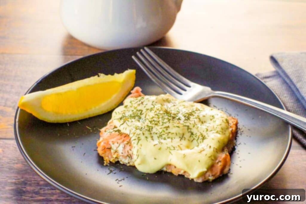 Lighter Hollandaise 8 healthy and low-fat Hollandaise sauce on salmon, on a black plate, with fork and wedge of lemon