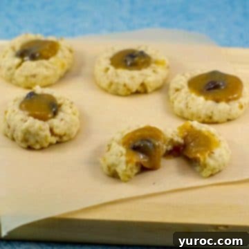 Delectable butter tart cookies arranged on parchment paper on a cutting board, with one cookie thoughtfully split in half to reveal its rich filling.