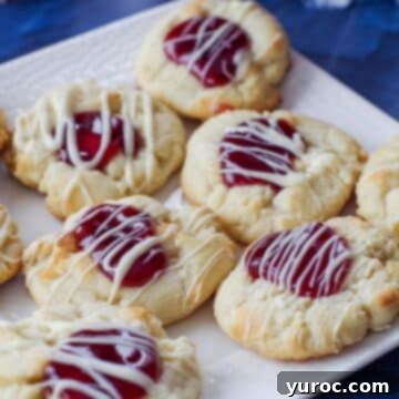 Exquisite white chocolate raspberry cookies, each drizzled with more white chocolate, presented on a pristine white plate.