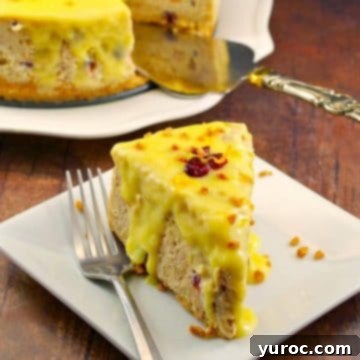 A delicious slice of cranberry bread pudding cheesecake on a white plate with a fork, and the remainder of the cheesecake in the background.