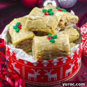 Festive Gingerbread Yule log cookies nestled inside a vibrant red and white Christmas cookie tin, ready for gifting.