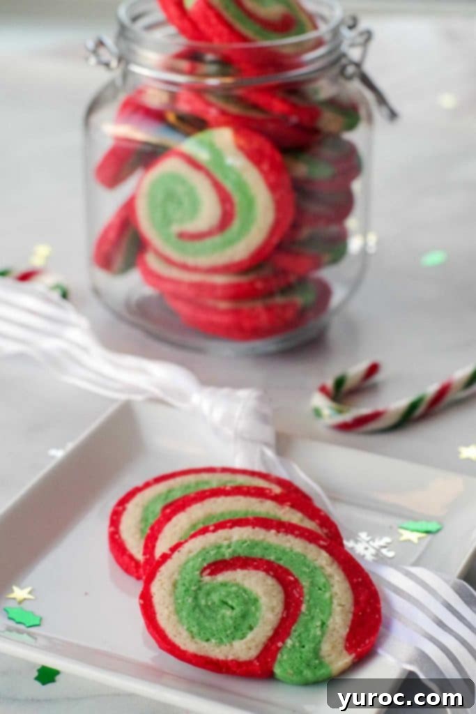 3 Christmas sugar swirl cookies on a plate with a jar of more cookies in the background