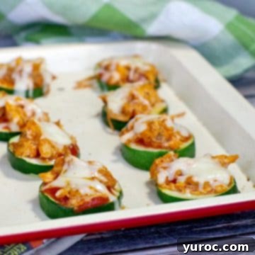 Delicious buffalo chicken zucchini pizza bites arranged on an off-white baking tray, ready for serving.