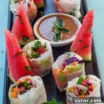 Watermelon Prosciutto Salad rolls, elegantly cut in half, arranged on a black platter, accompanied by fresh watermelon wedges.