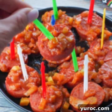 A slow cooker kielbasa appetizer being picked up with a green plastic skewer, highlighting its party-ready appeal.