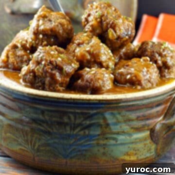 Succulent slow cooker sweet and sour meatballs presented in a rustic, handmade pottery serving bowl.
