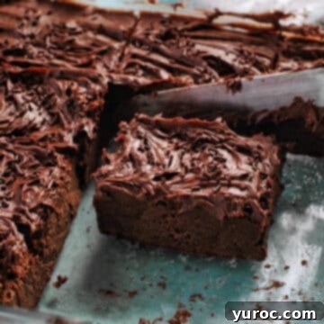 A decadent chocolate square being perfectly cut within a clear glass baking dish, ready for serving.