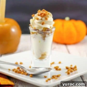 A delightful caramel apple betty dessert shot, beautifully presented on a white plate, with a fresh caramel apple and a small decorative pumpkin in the background.