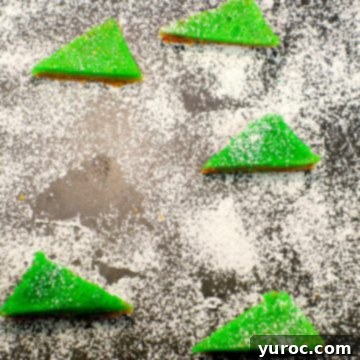 Festive lime squares dusted with powdered sugar, arranged on a cutting board, with a space where one square has been removed, hinting at its deliciousness.