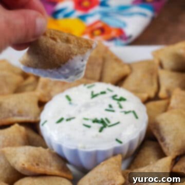 An air fryer pizza bite being dipped into sauce, with a tray of more delicious air fryer pizza bites visible in the background.