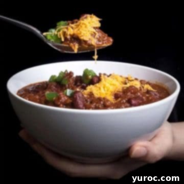 11 Legendary Chili Recipes 7 instant pot chili in a white bowl, with a spoon being held up over bowl
