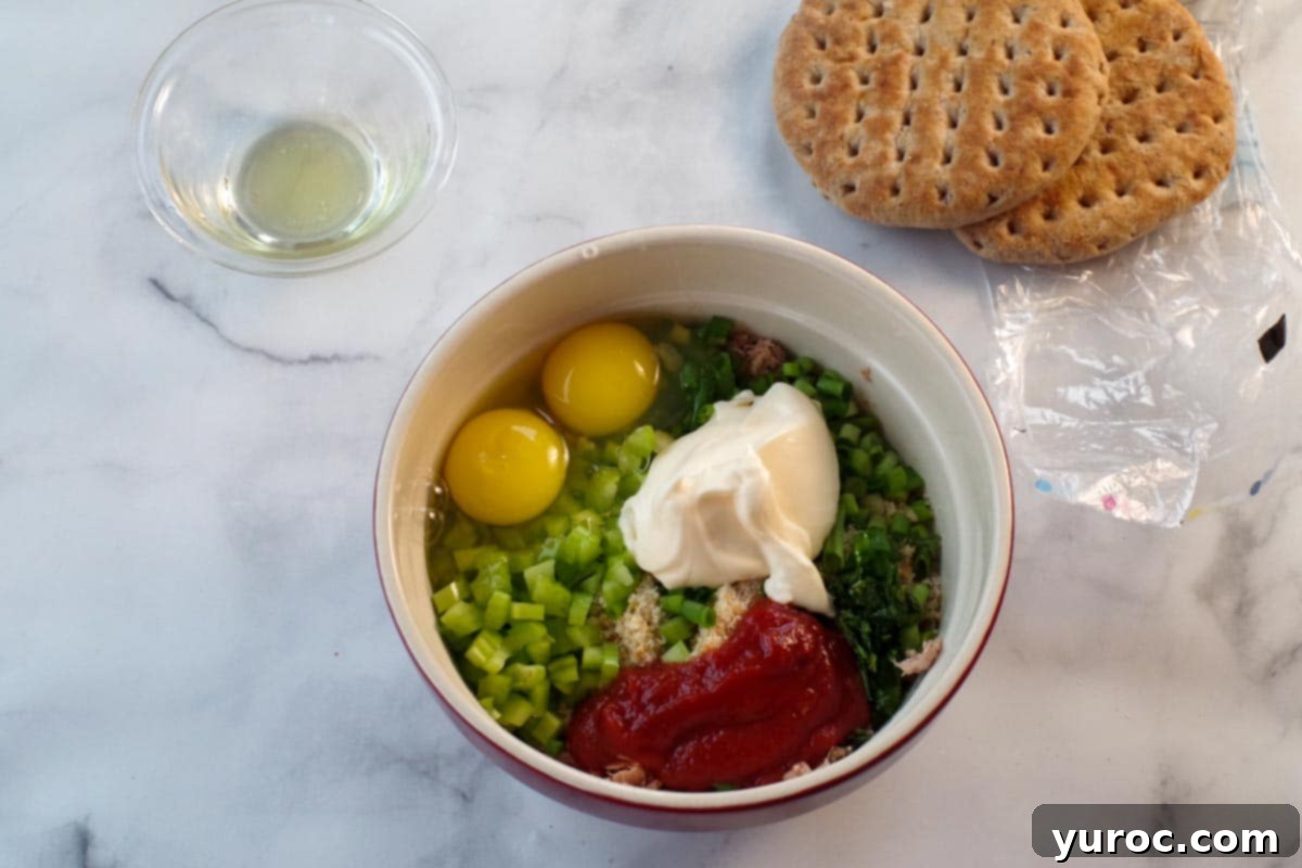 tuna burger ingredients in a bowl with buns and oil in the background