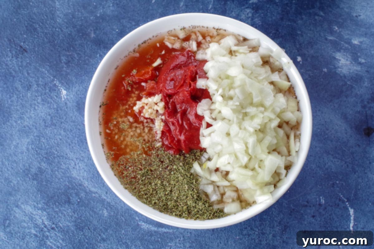 Rustic Baked Chicken Cacciatore 5 All chicken cacciatore sauce ingredients, including diced tomatoes, tomato paste, chopped onions, minced garlic, oregano, celery seed, and white wine, combined in a white mixing bowl.