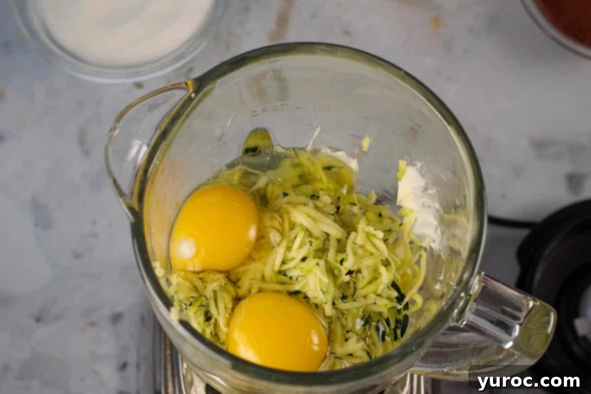 Blender Bliss Chocolate Zucchini Bread 5 Raw eggs, milk, shredded zucchini, and margarine placed inside a blender jar, ready for blending.
