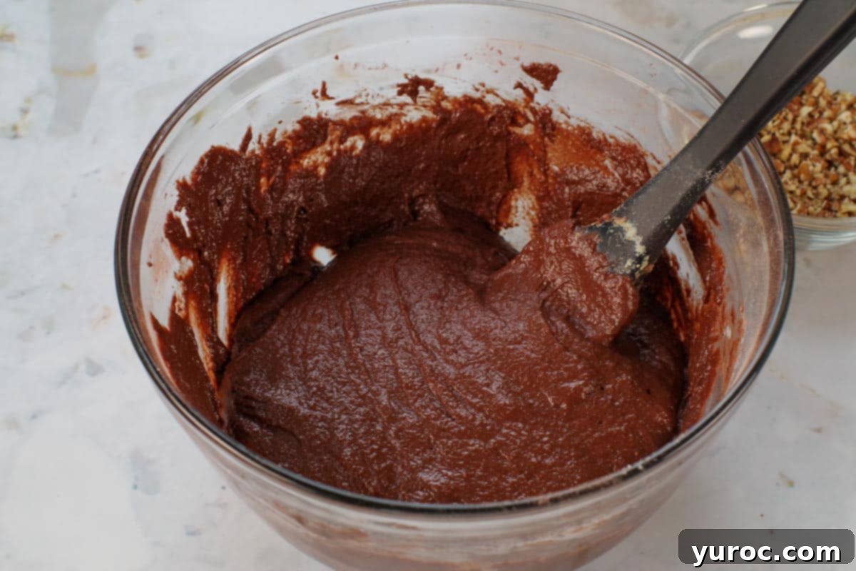 Blender Bliss Chocolate Zucchini Bread 9 The chocolate zucchini bread batter in a glass bowl, after the wet and dry ingredients have been mixed together, showing a smooth, consistent texture achieved with a black spatula.