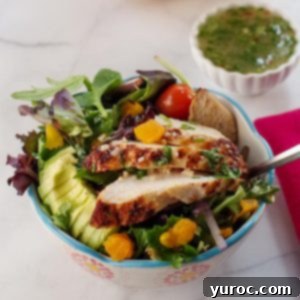 Fiery Cajun Mango Chicken Salad 10 cajun chicken avocado mango salad in a bowl with small dish of dressing in the background