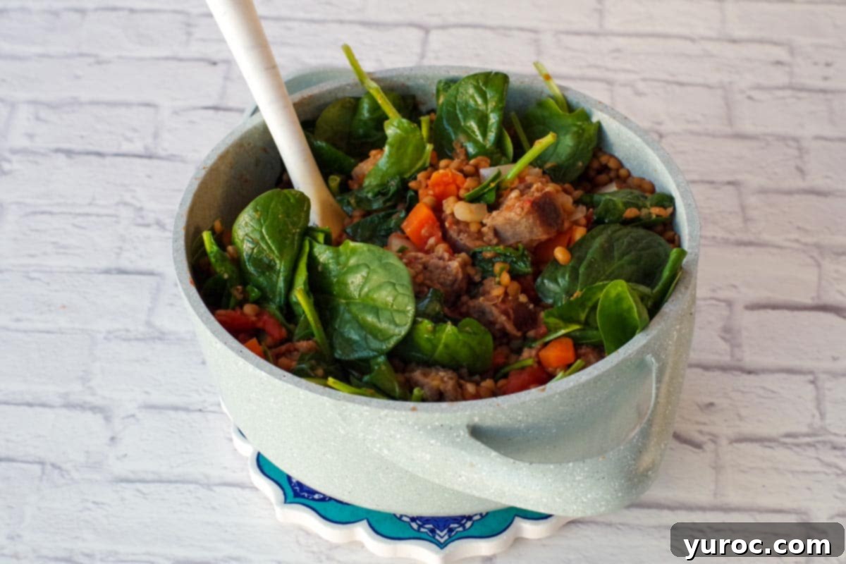 spinach being added to stew in batches