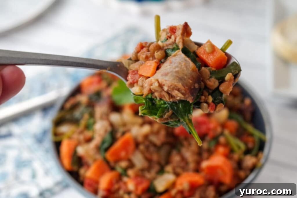 Lentil and Sausage stew (with spinach) being held up on a spoon)