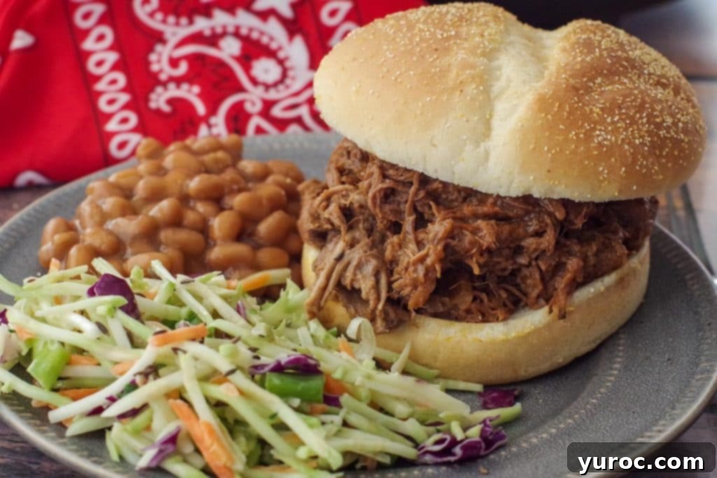 beef on a bun on a grey plate with coleslaw and beans