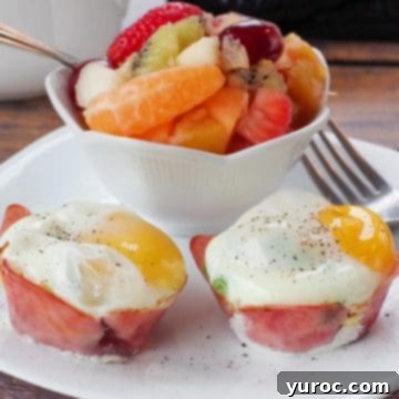 A perfectly portioned healthy Eggs Benedict served on a white plate, accompanied by a fork and a colorful bowl of fruit for a balanced meal.