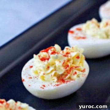 A perfectly prepared deviled egg, elegantly sprinkled with paprika, resting on a sophisticated black serving tray.