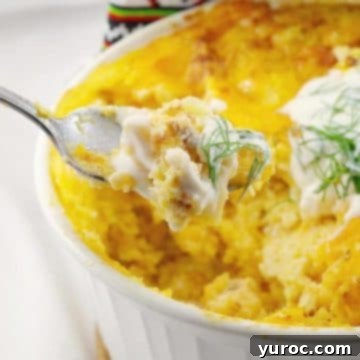 A frozen pierogi breakfast casserole in a white casserole dish, with a spoonful being held up to show the delicious layers.