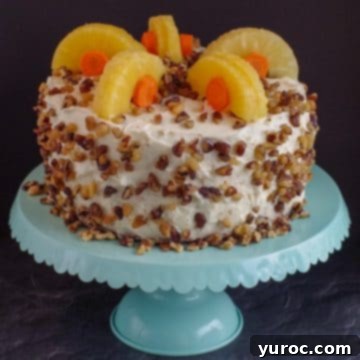 A beautifully decorated whole carrot cake, adorned with pineapple and carrots, proudly displayed on a charming aqua cake stand.
