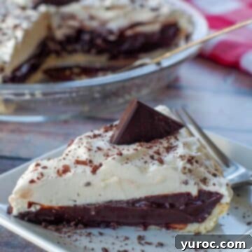 A delectable piece of old fashioned chocolate pie elegantly presented on a white plate with a fork, with the remainder of the pie visible in the background.