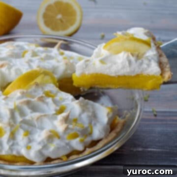 A perfect slice of old fashioned lemon pie being gently lifted out of a whole pie, with a fresh lemon cut in half resting in the background.