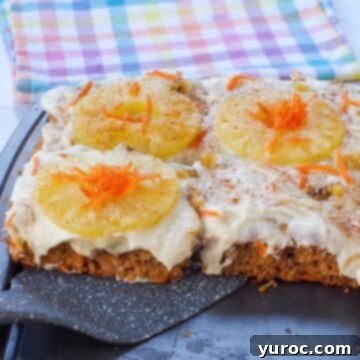 A slice of fluffy carrot cake pancake being lifted from a sheet pan, with a charming blue, yellow, and pink checkered tea towel in the background.