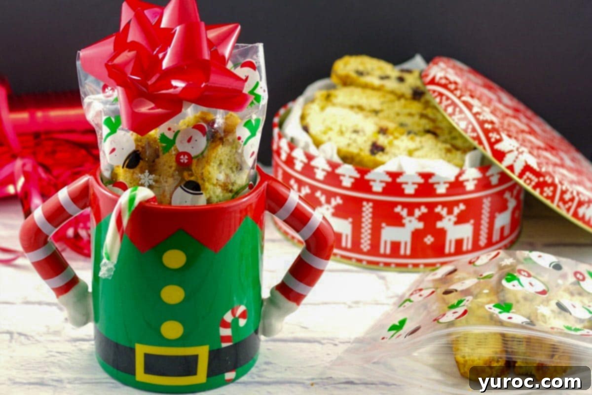 Christmas biscotti in a Christmas mug with a gift box of biscotti in the background, adorned with festive colors.