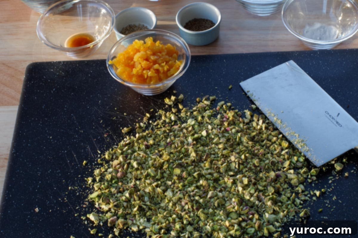 Pistachios chopped on a cutting board, with knife and apricot and other ingredients in background, ready for incorporation.
