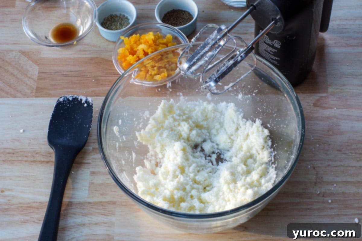 Softened butter being beaten with other ingredients in a glass bowl, illustrating the first mixing step.
