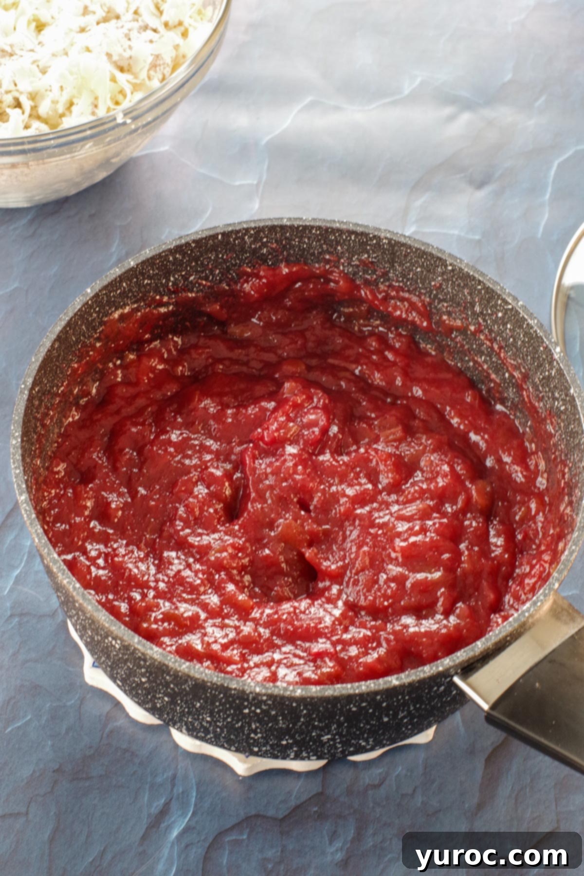 The rhubarb filling in a saucepan after red food coloring has been added, showing a more vibrant and appealing pink hue.