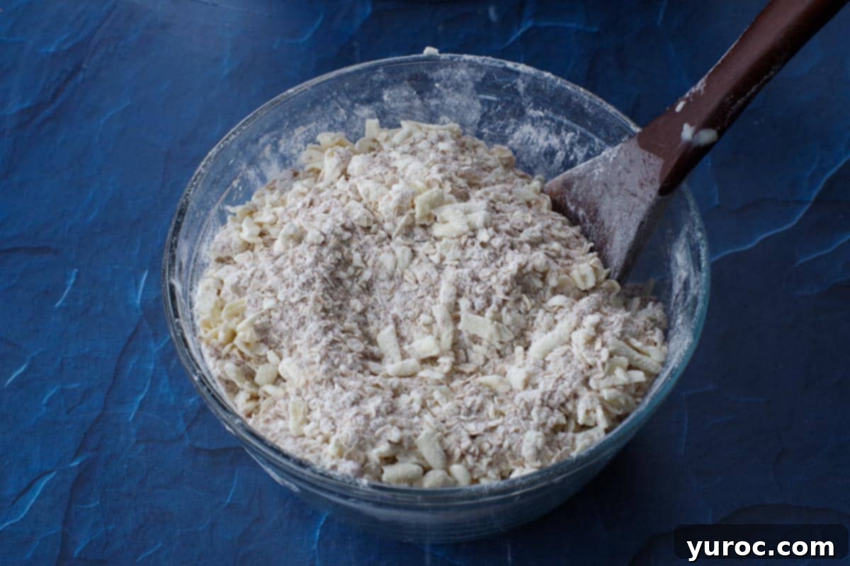 butter cut into flour mixture in a glass bowl with wooden spoon