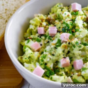 half a bowl of ham avocado and egg salad in a white bowl