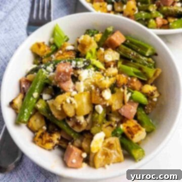 roasted turnip and asparagus salad in a white bowl with fork on the side