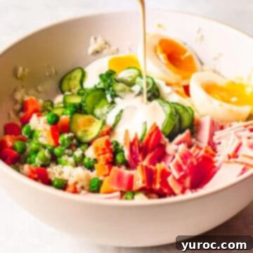 Japanese Potato Salad in a white bowl with dressing being poured on top