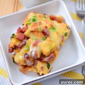 a piece of cheesy breakfast ham casserole on a white plate