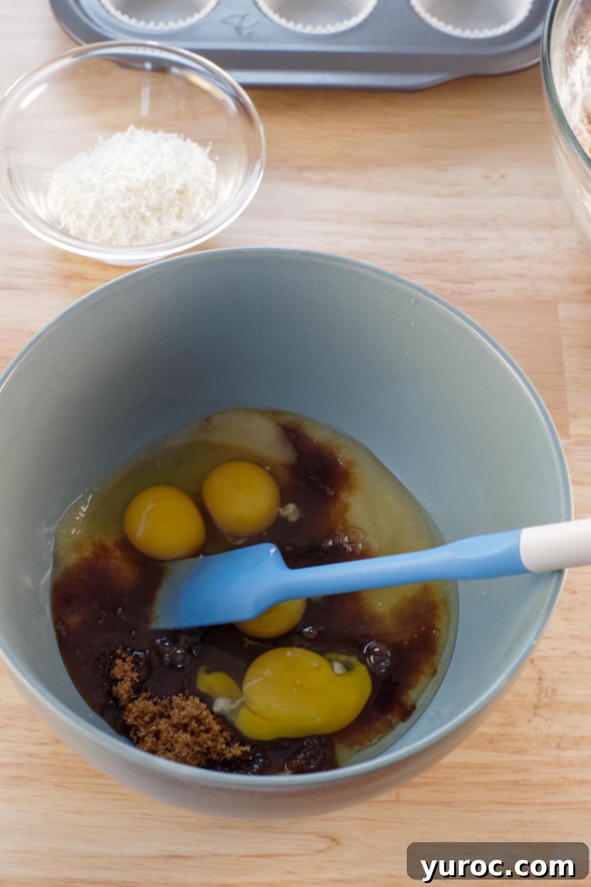 blue mixing bowl with wet ingredients and blue spatula