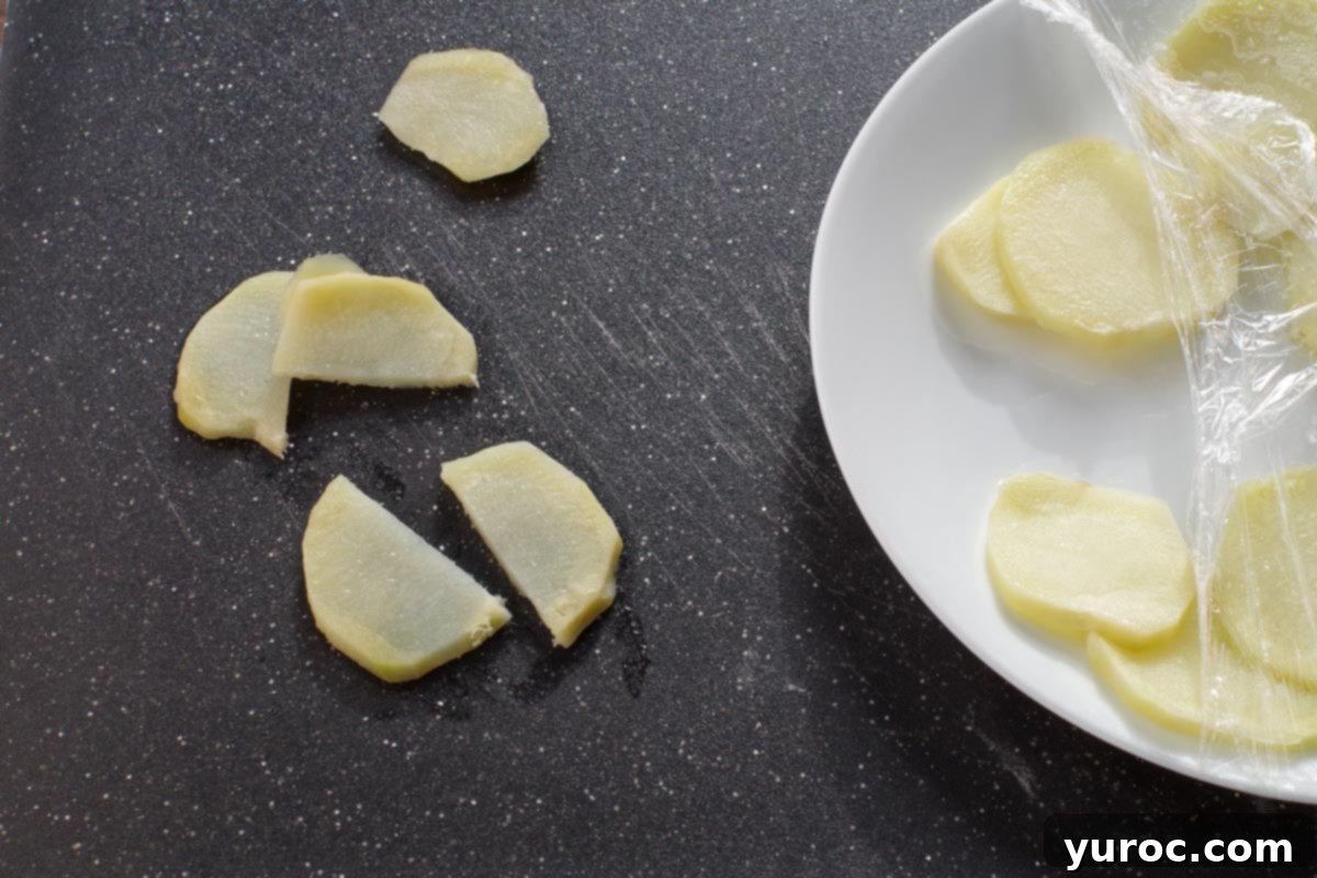 Cooked potato slices, now tender and halved into smaller, rustic pieces, neatly arranged on a cutting board, ready to be incorporated into the pizza.