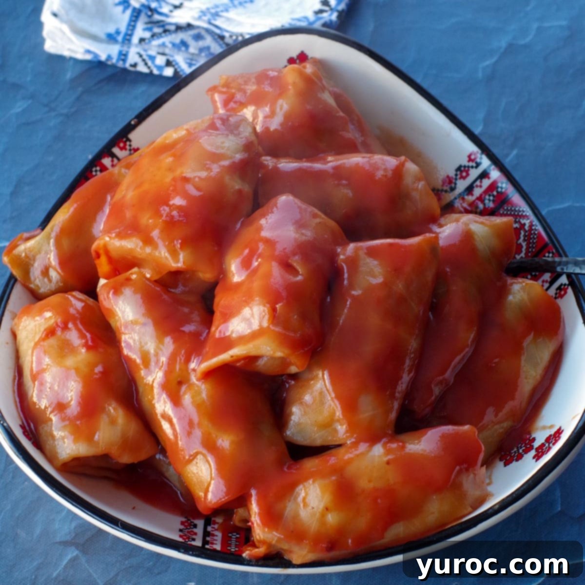 stacked cabbage rolls in a triangular Ukrainian print dish, on a blue surface