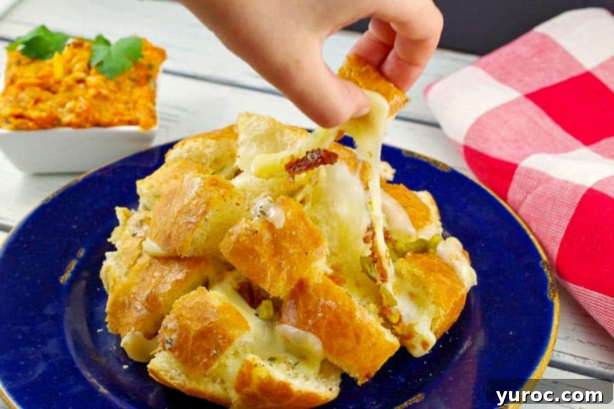 hand pulling a piece of Cheesy pull apart bread from bun