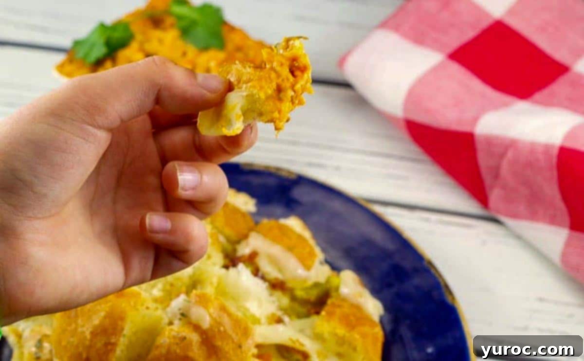 hand pulling a piece of Cheesy pull apart bread from bun, with dip on it